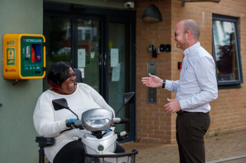 Picture of Greatwell Homes staff member and Involved customer, who is in a mobility scooter, talking and laughing
