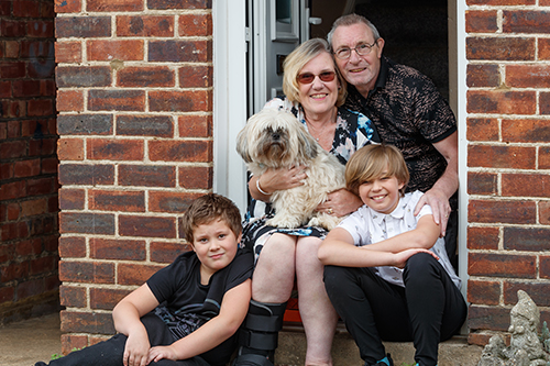 A family who live in a Greatwell Homes property, with their dog, smiling at the camera. Greatwell Homes allows customers to keep a pet in their homes, in line with the pet policy.